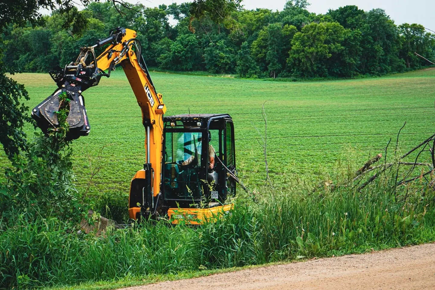 TreeTec excavator fitted with a grapple attachment working a treeline